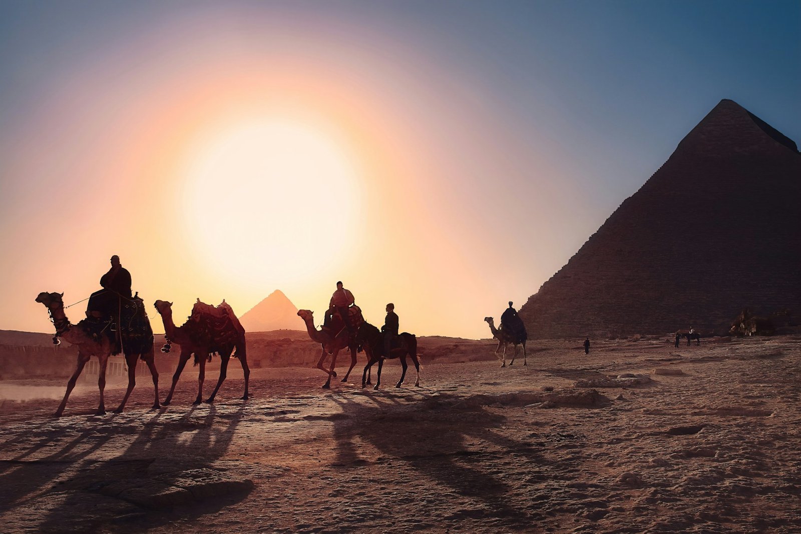 Camel caravan passing the Great Pyramid of Giza at sunset